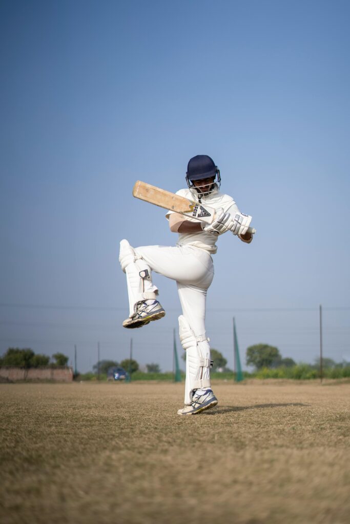 pexels-photo-10987828-10987828 Cricket player swinging bat on a sunny field, showcasing athletic skill.